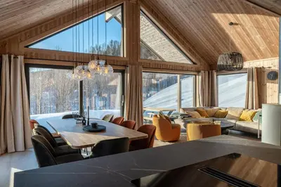 a living room with a table and chairs and large windows at Spacious lodge with sauna, ski centre in Noresund