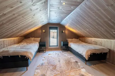 two beds in a room with wooden walls at Spacious lodge with sauna, ski centre in Noresund