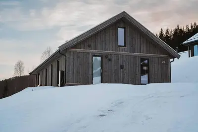 a wooden house in the snow in front at Spacious lodge with sauna, ski centre in Noresund