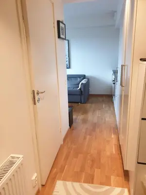 a hallway leading to a living room with a blue couch at Modern apartment in Trondheim