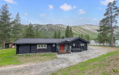 a black house with a red door in a field at 4 Bedroom Cozy Home In Nordberg in Nordberg