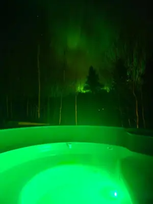 a green bath tub with a green light in the sky at Lykke House Hot Tub, Grill Hut Northern Lights in Trysil
