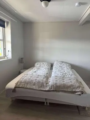 a bed in a bedroom with a white wall at Korssundvegen 230 in Korssund