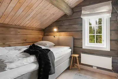 a bedroom with a bed in a wooden cabin at Trysilfjell 811 by Vacation Trysil in Trysil