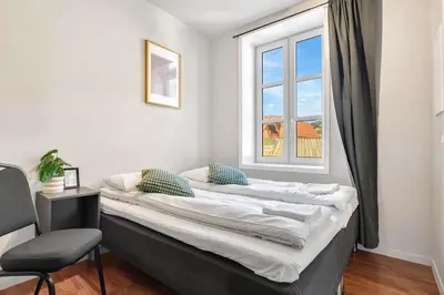 a bed in a room with a window and a chair at Harbour - 1BR Apartment in Bergen