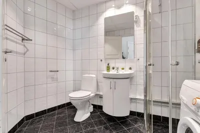 a white bathroom with a toilet and a sink at Harbour - 1BR Apartment in Bergen