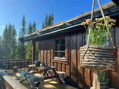 a log cabin with a table and a basket with flowers at Newly Renovated Cabin By Sjusjoen Ski Slopes in Sjusjøen