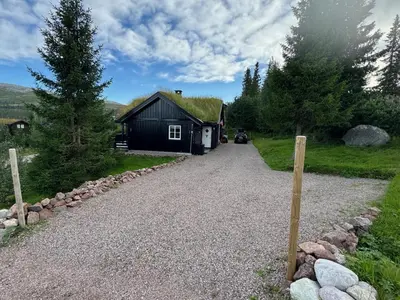 a house with a grass roof on a gravel driveway at Cosy ski-in ski-out mountain cabin with sauna in Trysil