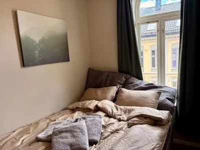 an unmade bed in a room with a window at Apartment in apartment building, close to the train station in Bergen