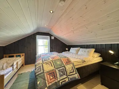 a bedroom with a large bed in a attic at Bjørnebo, Family cabin in Torpo