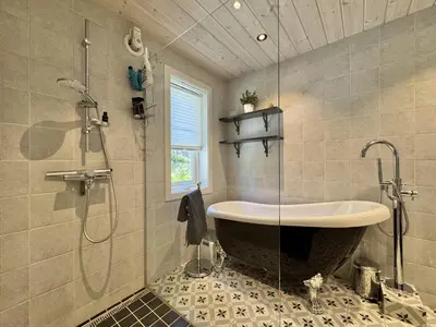 a bathroom with a large tub and a shower at Bjørnebo, Family cabin in Torpo