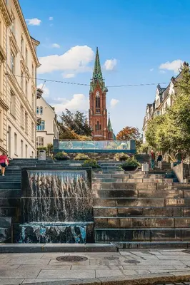 a fountain in front of a building with a clock tower at DINBNB Apartment l 200m to Torgallmenningen l High-End Bergen Stay l Steps from Center in Bergen