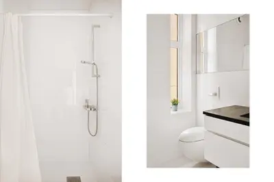 a white bathroom with a shower and a toilet at DINBNB Apartment l 200m to Torgallmenningen l High-End Bergen Stay l Steps from Center in Bergen