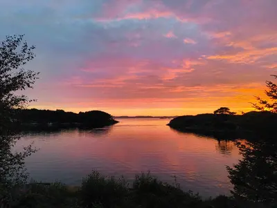 a sunset over a body of water with trees at Retreat Øklandsnes in Lii