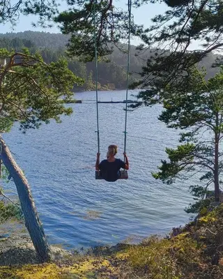 a person sitting on a swing in a lake at Retreat Øklandsnes in Lii