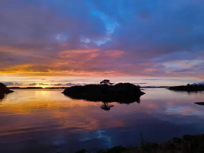 an island in a body of water with a sunset at Retreat Øklandsnes in Lii