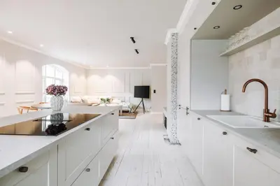 a white kitchen with a sink and a living room at Large city apartment with sea view and parking in Ålesund