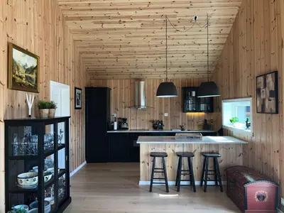 a kitchen with wooden walls and a island with bar stools at 12 person holiday home in Skare-By Traum in Skare