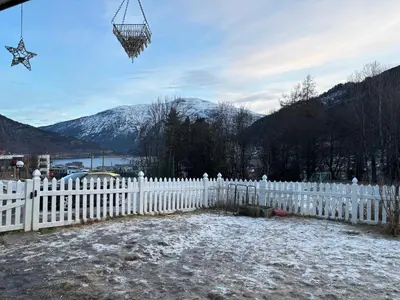 a white picket fence with a snowy mountain in the background at Solsiden apartment in Sogndal