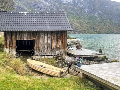 a wooden shack with a boat next to a dock at 3 person holiday home in STRYN-By Traum in Stryn