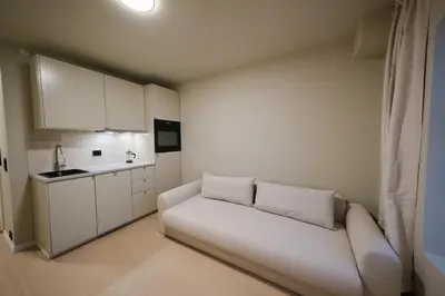 a white couch in a small room with a kitchen at Cozy and practical studio in the city center in Ålesund
