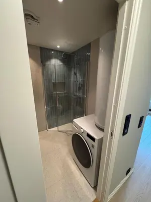 a bathroom with a shower and a washing machine at Cozy and practical studio in the city center in Ålesund