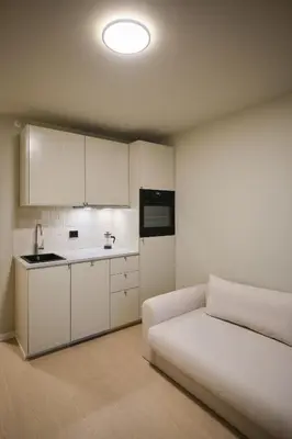 a room with a bed and a kitchen with white cabinets at Cozy and practical studio in the city center in Ålesund