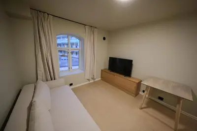 a bedroom with a bed and a tv and a window at Cozy and practical studio in the city center in Ålesund