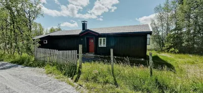 a small black house in a field next to a road at Mountain Cabin With Panoramic Views In Brakastølen in Ron