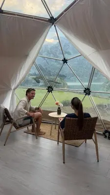 a man and woman sitting in chairs in a tent at Vollsnes Glamping in Stryn