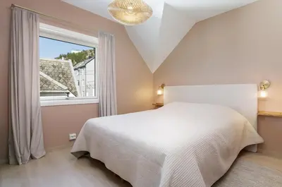a bedroom with a white bed and a window at Fjord Vista - Top floor apartment in Ålesund in Ålesund