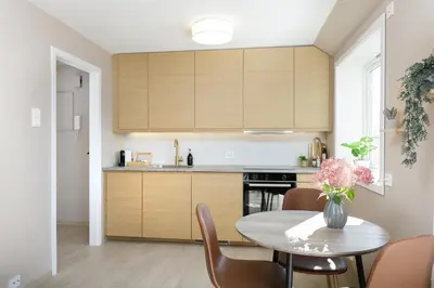 a kitchen with wooden cabinets and a table with chairs at Fjord Vista - Top floor apartment in Ålesund in Ålesund