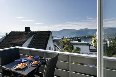 a table with plates of food on top of a balcony at Fjord Vista - Top floor apartment in Ålesund in Ålesund