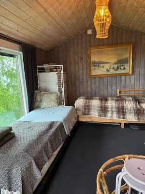 a bedroom with two beds and a table and a chandelier at Idyllic cottage with a view, close to Gardermoen Airport in Hurdal
