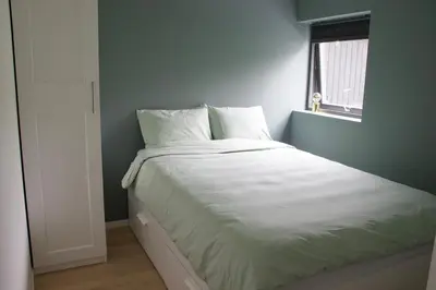 a bed with white sheets in a room with a window at Moderne hus - sentralt, rolig med gratis parkering in Bergen