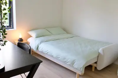 a bed in a white room with a table and a bed at Moderne hus - sentralt, rolig med gratis parkering in Bergen