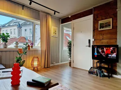 a living room with a television and a large window at Historic charm in the heart of Bergen in Bergen