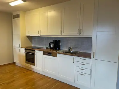 a kitchen with white cabinets and a sink at Sentral Og Moderne Leilighet Med Heis Og Garasje in Beitostøl