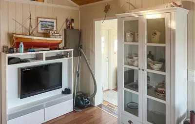 a living room with a tv in a white cabinet at Nice Home In Sauøya With House Sea View