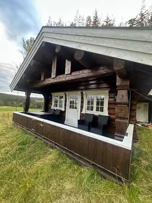 a log cabin with white doors and windows in a field at Peaceful cabin with secluded location in Ål