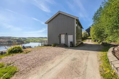 a small building on a dirt road next to a river at The top half of a house with sea view in Steinkjer