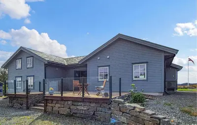 a gray house with a deck in front of it at Beautiful Home In Fitjar With House Sea View in Fitjar