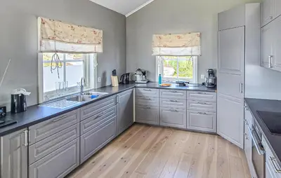 a kitchen with white cabinets and a wooden floor at Beautiful Home In Fitjar With House Sea View in Fitjar