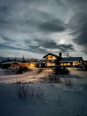 a large house in the snow with lights on at Log Cabin Near Høgevarde With Mountain Views in Flå