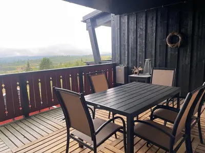 a wooden table and chairs on a balcony with a table and chairs at Stor Og Moderne Leilighet I Sentrum in Beitostøl