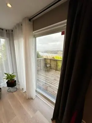 a room with a large window with a view of a deck at Cozy house with a sea view in Knarrvika