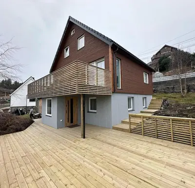 a house with a wooden deck in front of it at Cozy house with a sea view in Knarrvika