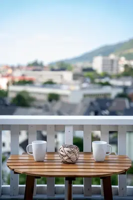 a wooden table with two coffee cups on a balcony at Privat rom i koselig Bergenshus in Bergen