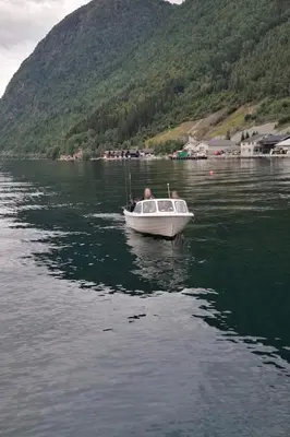 a man in a boat on a body of water at Koselig ved Fjorden - Vangsnes in Vangsnes