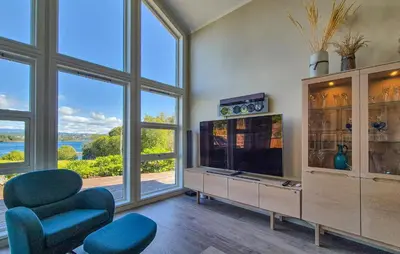 a living room with a tv and some chairs and windows at Beautiful Home In Bjørøyhamn With House Sea View in Nord Bjørøy